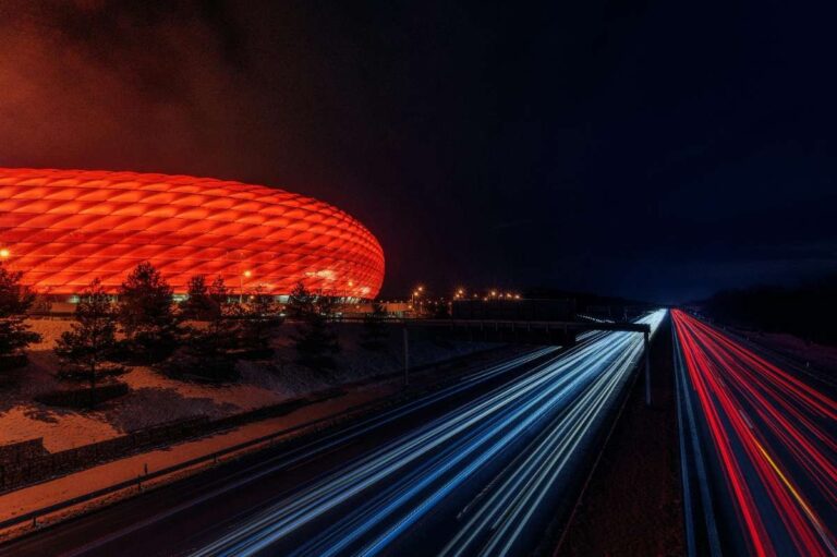 Allianz Arena in Munich lit red at night with highway light trails