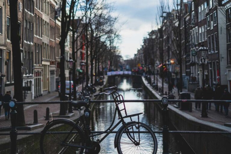 A bicycle rests on a bridge railing over a canal in Amsterdam