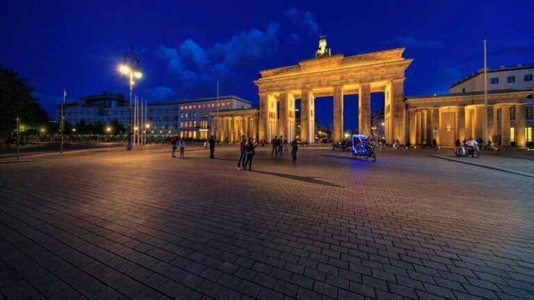 Brandenburg Gate lit up at night with people in the square