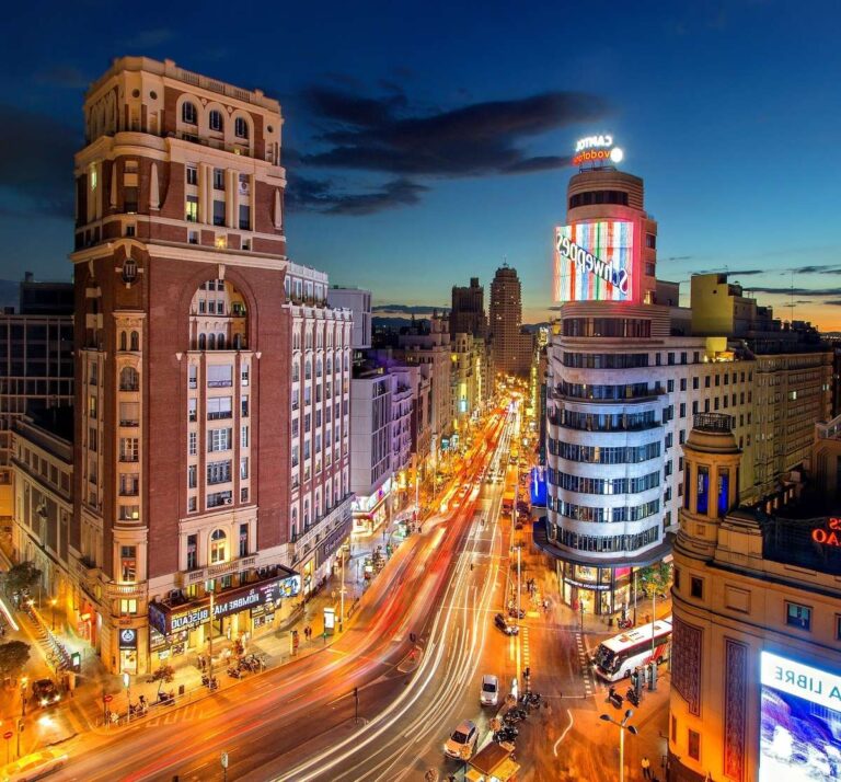 Vibrant night scene on Gran Via in Madrid, with colorful lights and bustling traffic