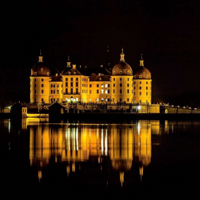 Castle in St. Moritz illuminated at night with reflections on water