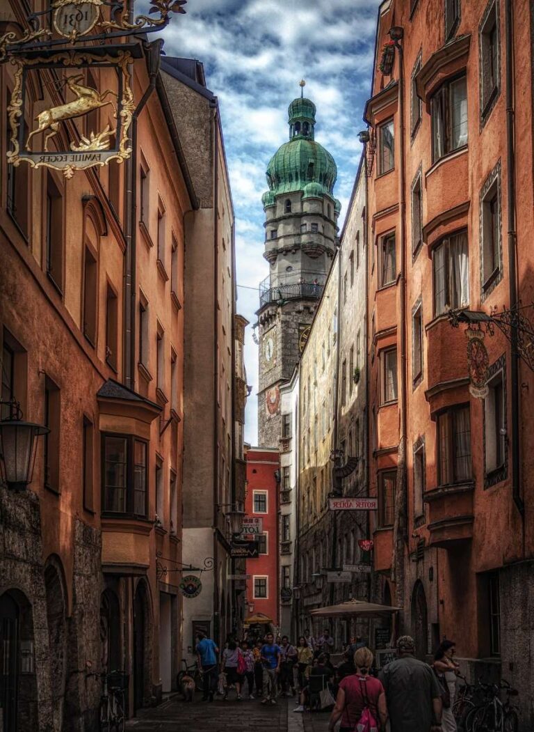 Narrow street in Innsbruck with pastel-colored buildings and a green-domed tower