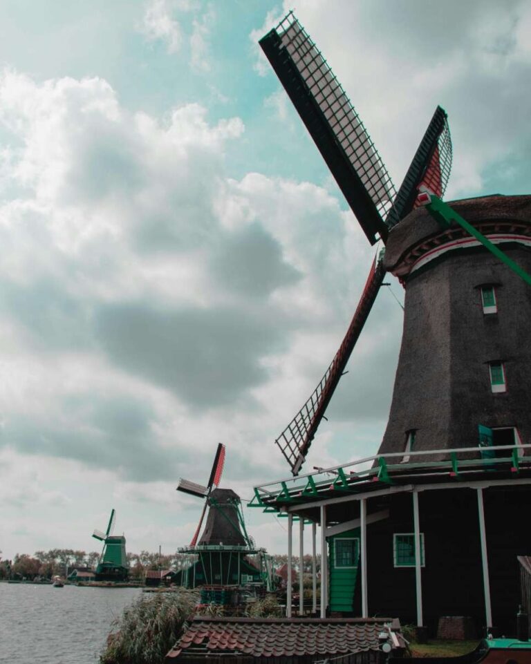 Traditional Dutch windmills under a cloudy sky near a river