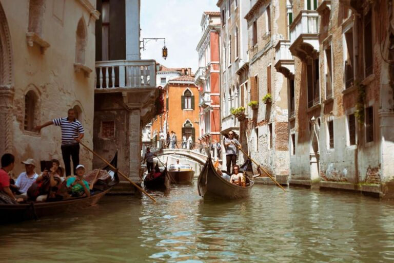 Tourists enjoy a gondola ride through a narrow canal in Venice