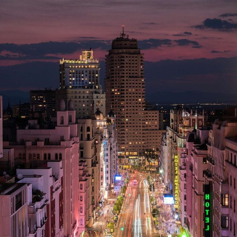 Night view of Madrid's Gran Via with illuminated buildings and traffic light trails