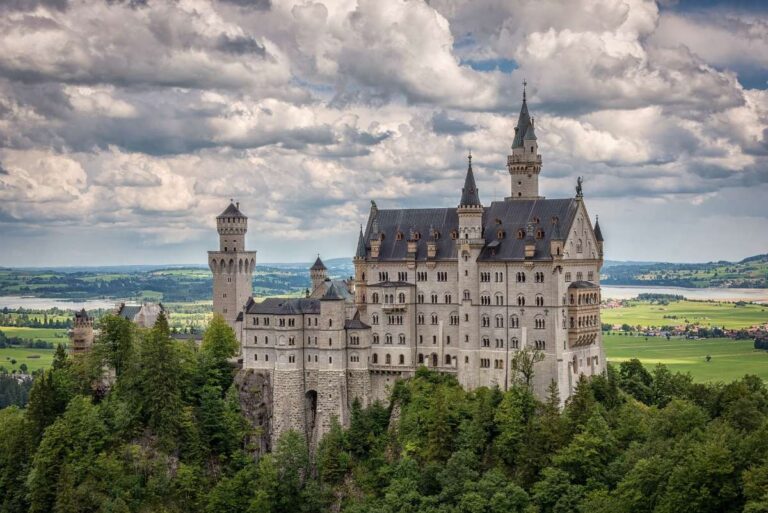 Neuschwanstein Castle perched on a lush hillside under a cloudy sky