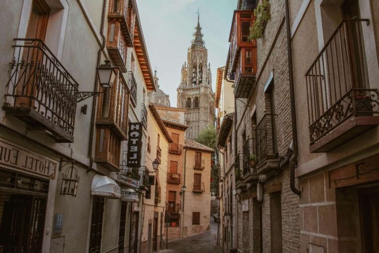 Narrow street in Toledo with hotel sign and distant cathedral