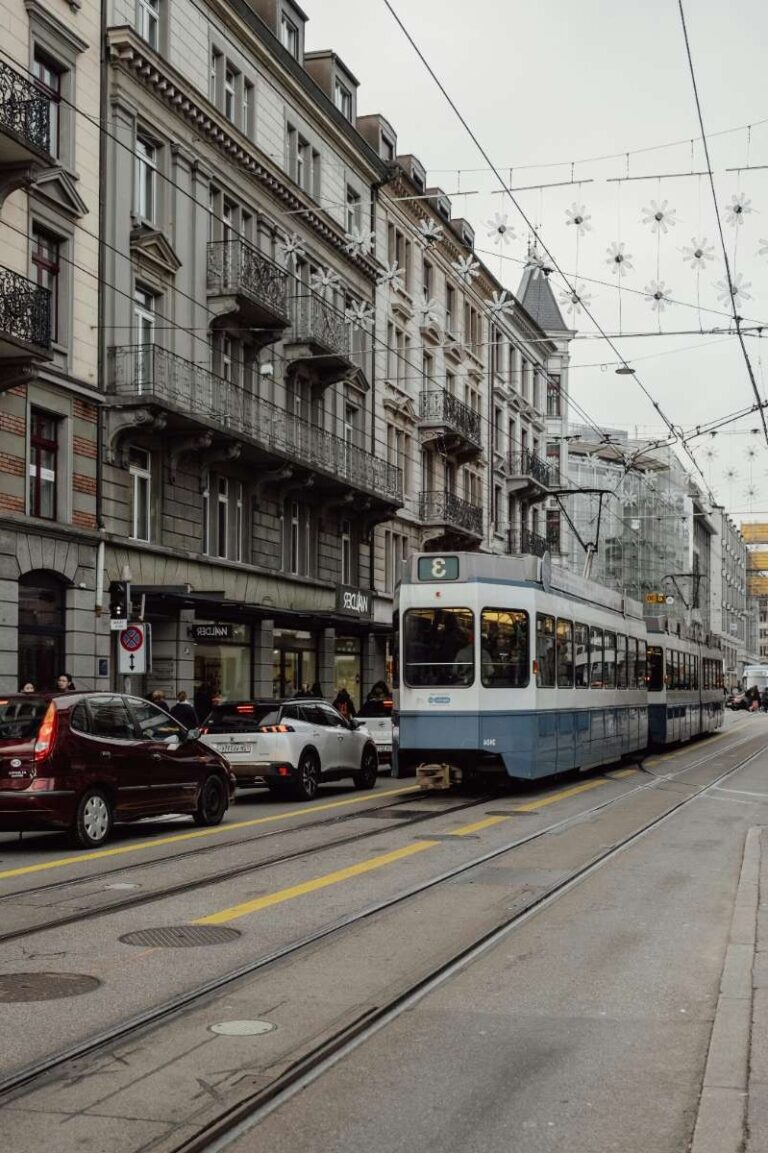 Tram and cars on a bustling street lined with historic buildings in Zurich