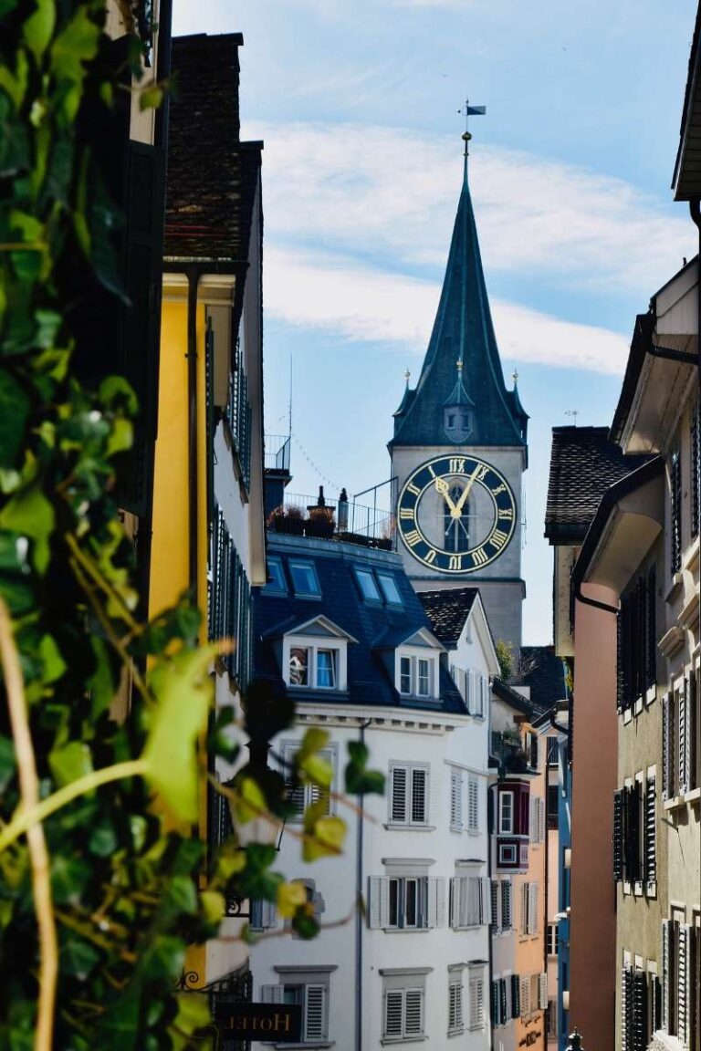 A clock tower peeking through the narrow streets of Old Town Zurich