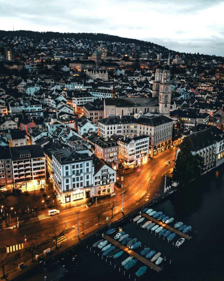 Aerial view of Zurich city with a prominent church and surrounding hills