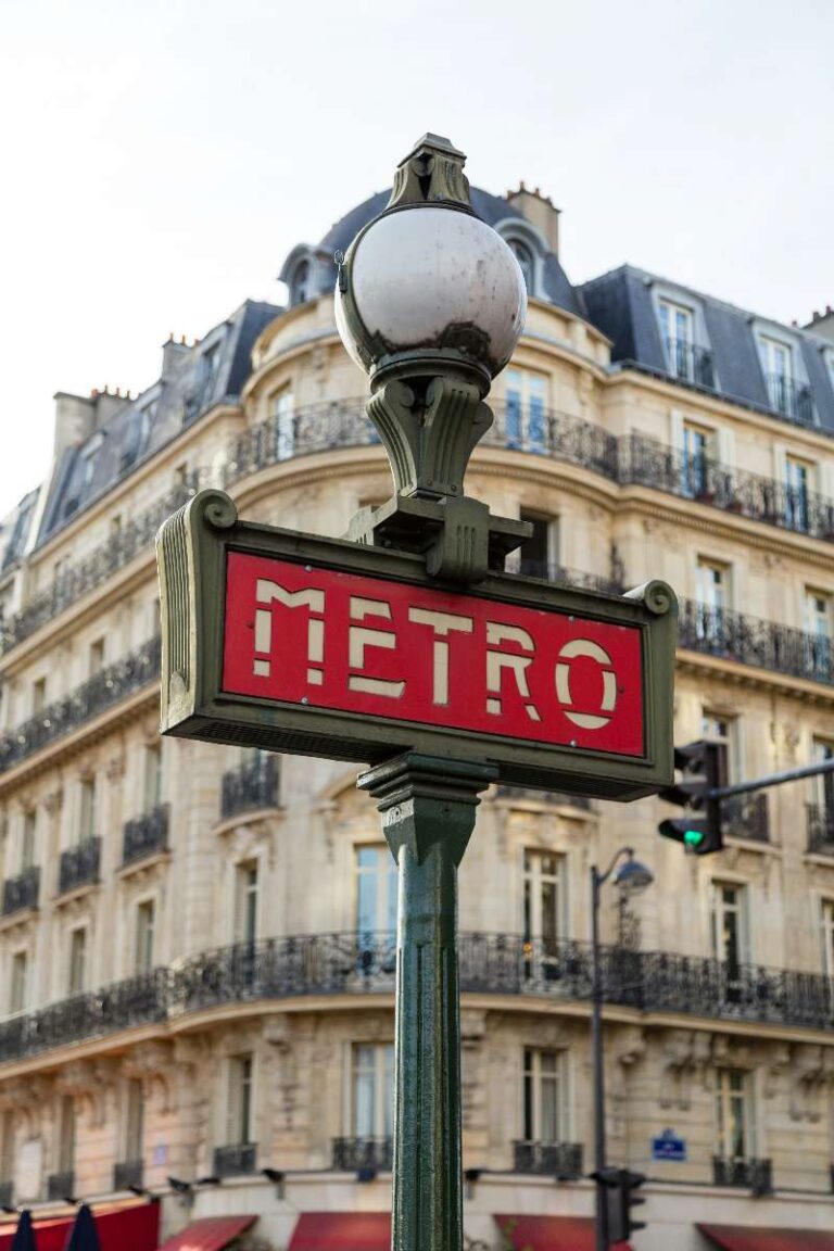 Classic Paris metro sign in front of a Haussmann-style building