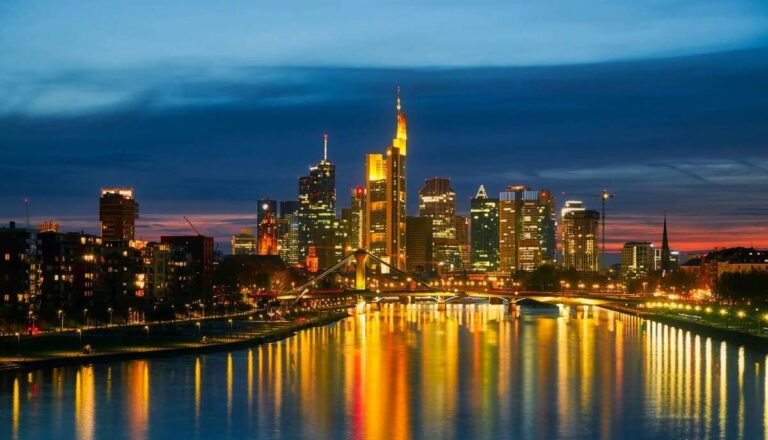 Frankfurt skyline at night with skyscrapers illuminated and reflections on the river