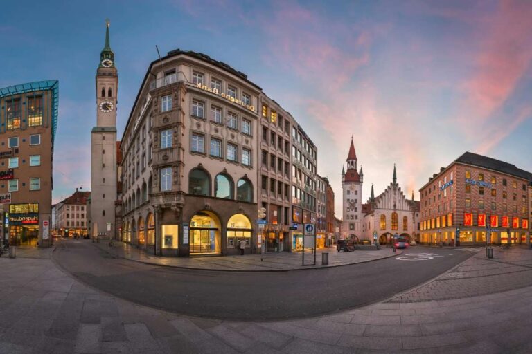 A city square with historic buildings and a clock tower at dusk in Munich