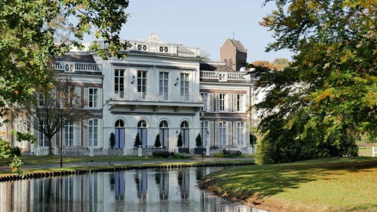 Historic residence in Arnhem surrounded by trees and a calm reflecting pond