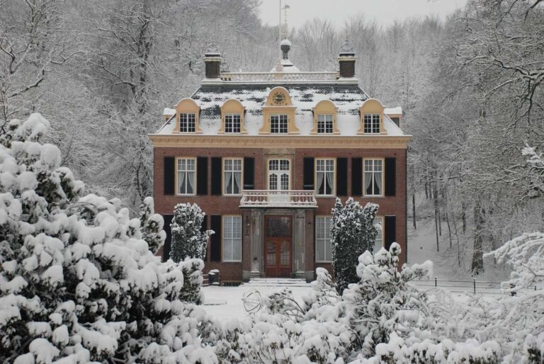 A traditional Dutch residence in Arnhem blanketed with snow and surrounded by trees