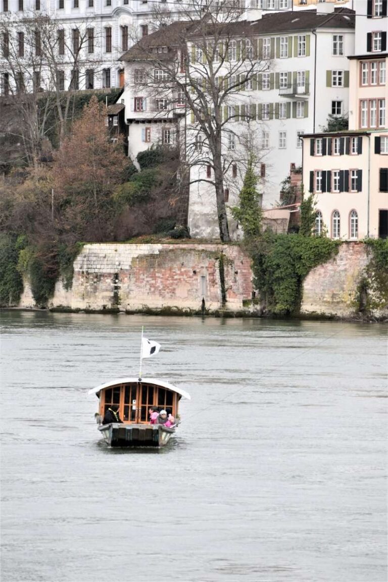 Small boat on the Rhine River passing by scenic, historic buildings