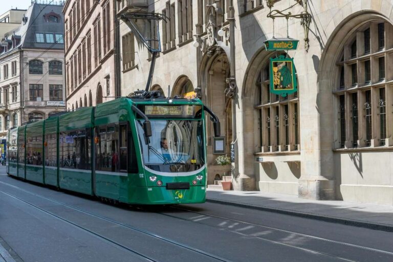 Green tram moving through Basel's historic city center