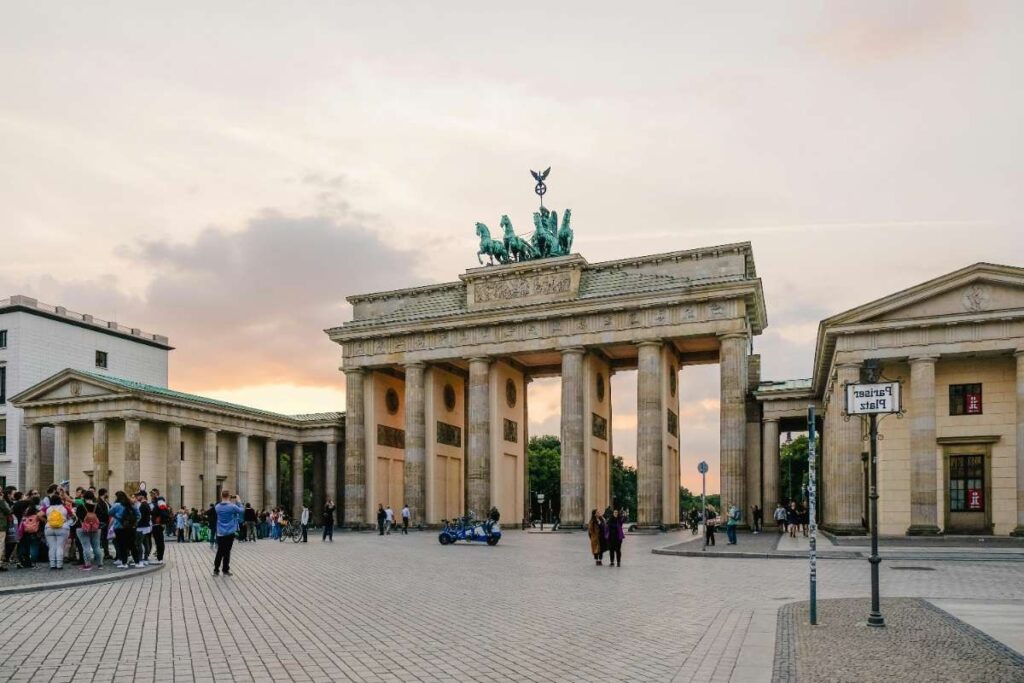 People gather at Berlin's Brandenburg Gate during sunset