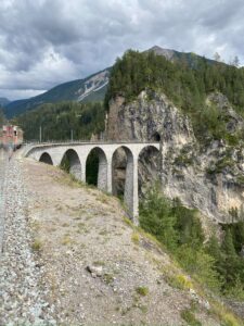 Train crossing a stone viaduct over a forested gorge