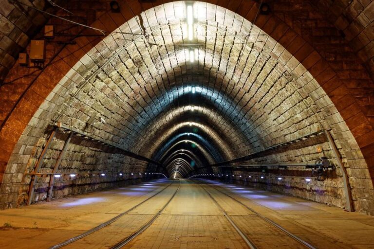 Tram tracks inside a stone-arched tunnel with lights