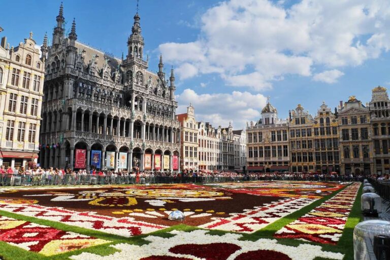 Crowded Grand Place square in Brussels adorned with a vibrant flower carpet