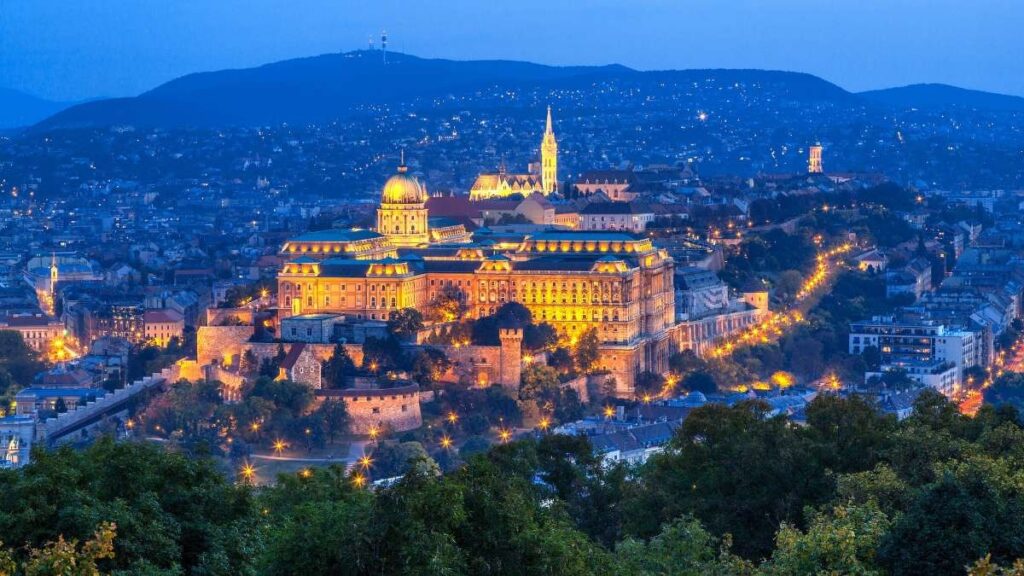 Budapest Castle illuminated at night with a cityscape backdrop