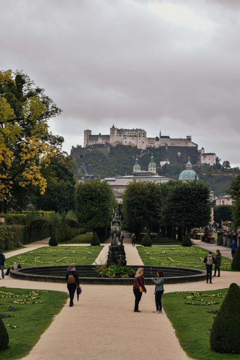 View of Hohensalzburg Fortress above gardens and trees on a cloudy day