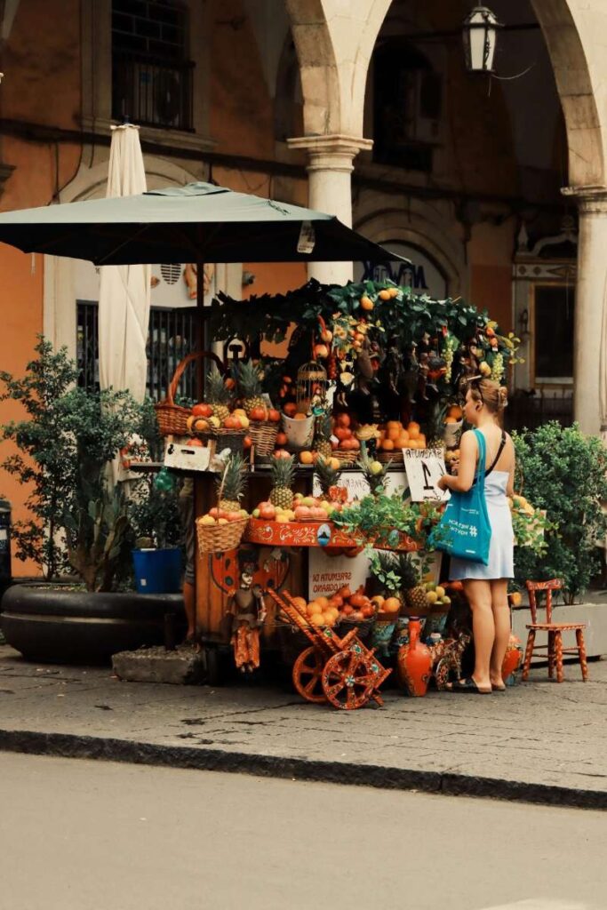 A woman shops at a colorful fruit stall in a street market