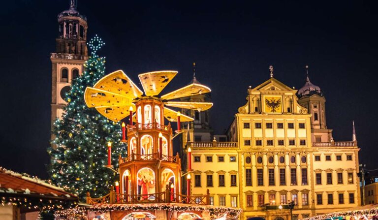 Christmas market with large tree and illuminated decorations at night in Augsburg