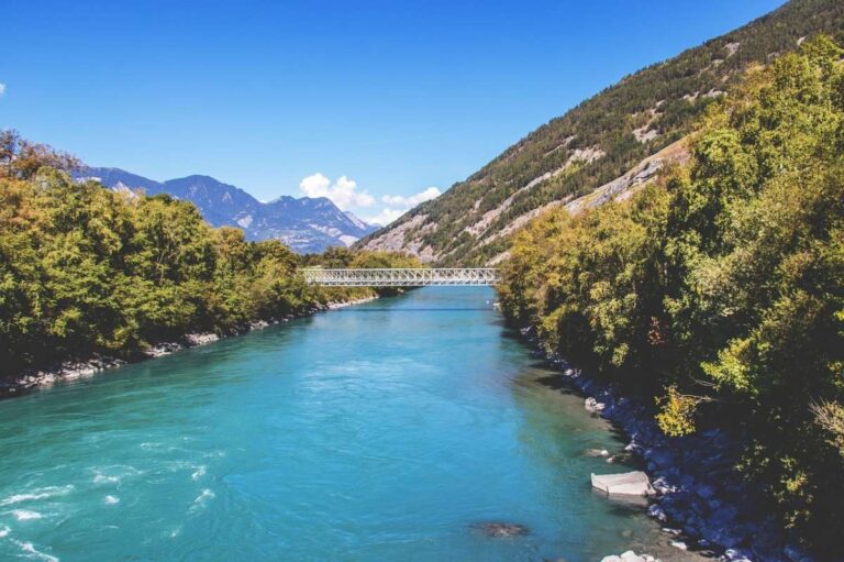 Turquoise river flowing through a valley with mountains in the distance