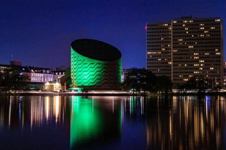 A nighttime view of a river with buildings lit up in Copenhagen