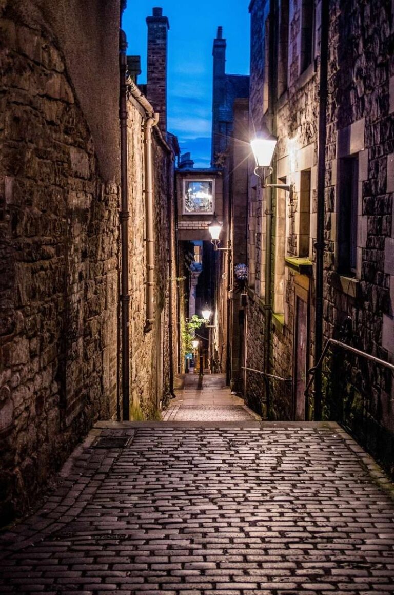 A narrow cobblestone alley with lanterns in Edinburgh Old Town