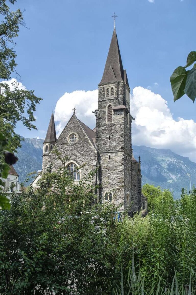 Gothic church with tall spires surrounded by greenery