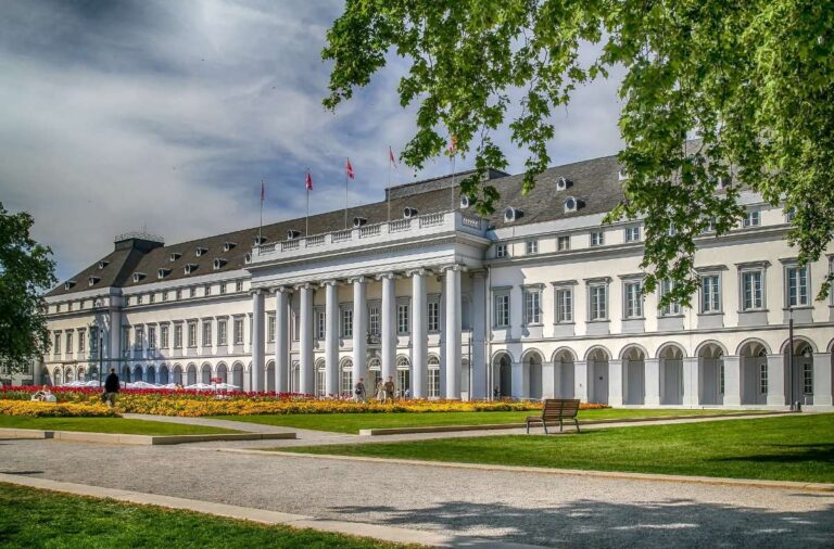 Beautiful white palace with columns surrounded by a vibrant flower garden