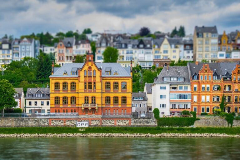 Colorful buildings by the riverbank in Koblenz with a cloudy sky overhead