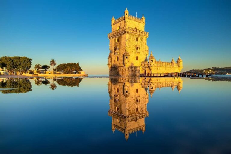 Belem Tower reflecting in calm water under a clear blue sky