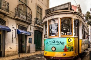 Historic Lisbon tram running through narrow streets at dusk