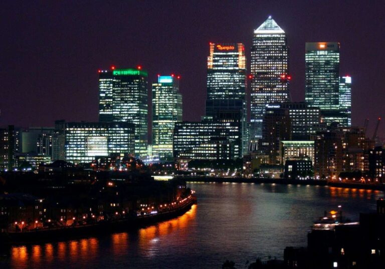 Illuminated London skyline at night with reflections in the River Thames