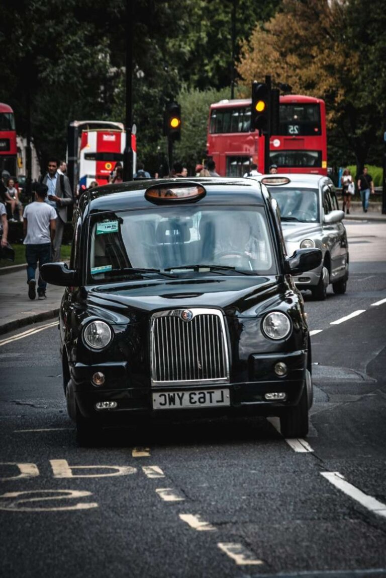 Classic black London cab on a bustling city street with red buses