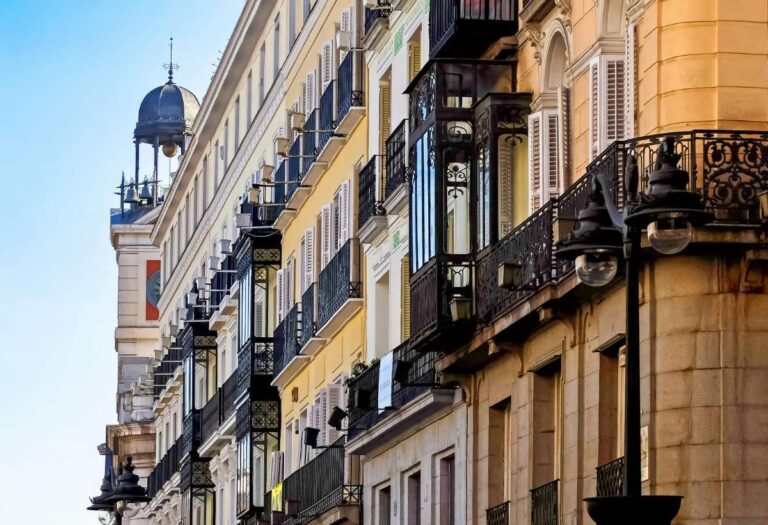 Row of traditional Madrid houses with ornate iron balconies and shutters