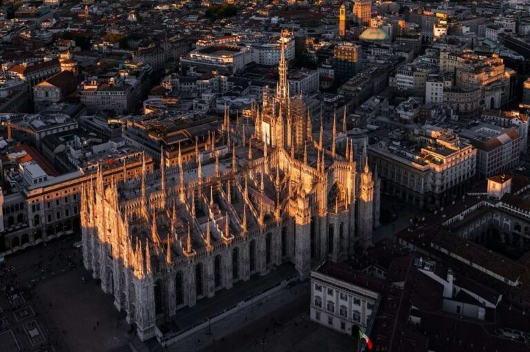 Aerial view of Milan Cathedral bathed in evening light amidst city buildings