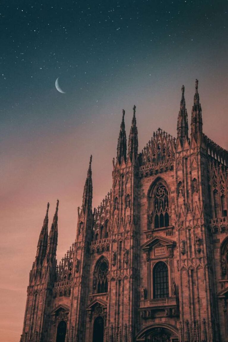 The Milan Cathedral illuminated under a starry sky at dusk