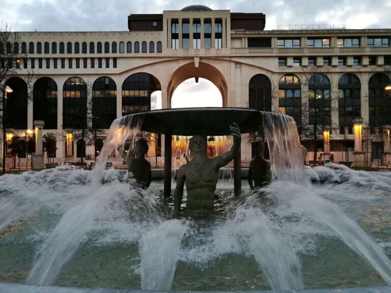 Fountain with statues and cascading water in front of a modern building