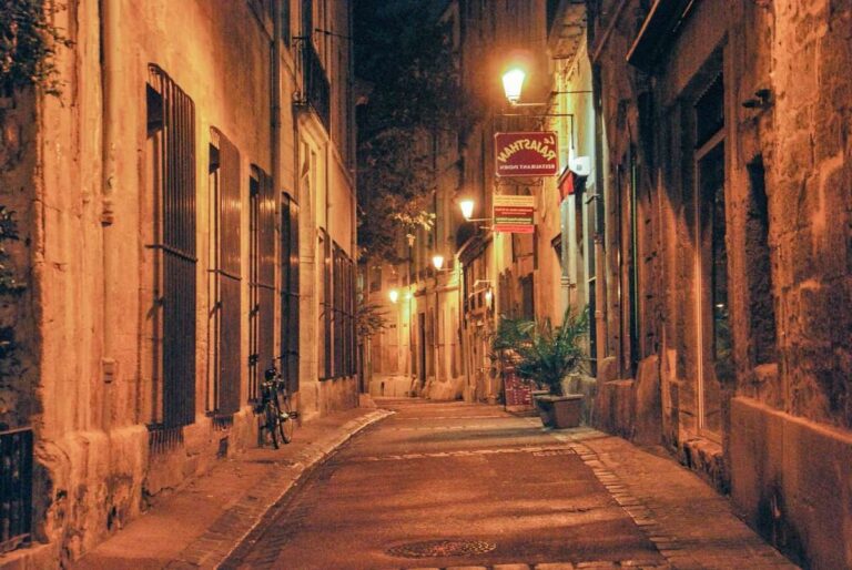 Narrow, dimly lit street in Montpellier's historic city center at night