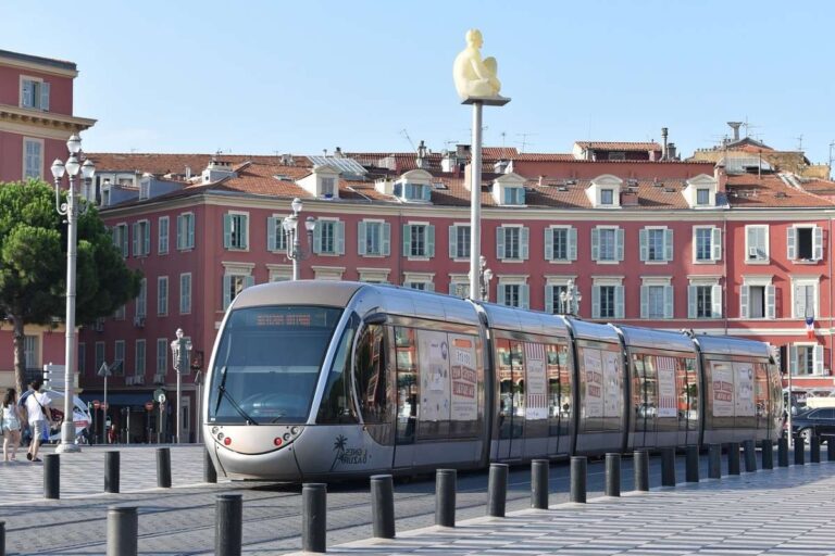 Modern tram gliding through a busy city square lined with colorful buildings