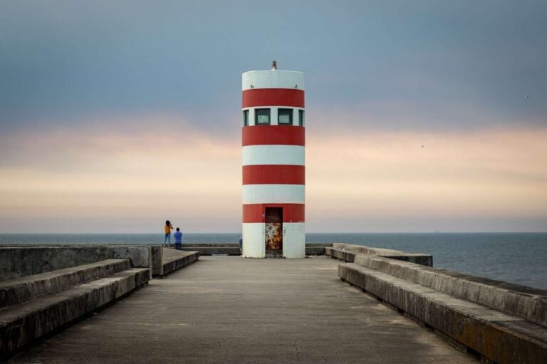 Red and white striped lighthouse on the ocean in Porto