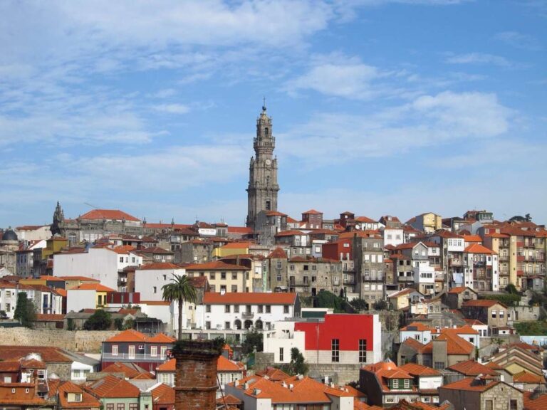 Panoramic view of Porto with a tall church tower and red-roofed buildings