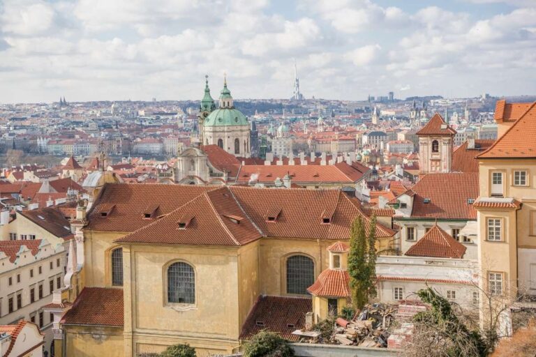 Prague cityscape with red rooftops and church domes on a cloudy day