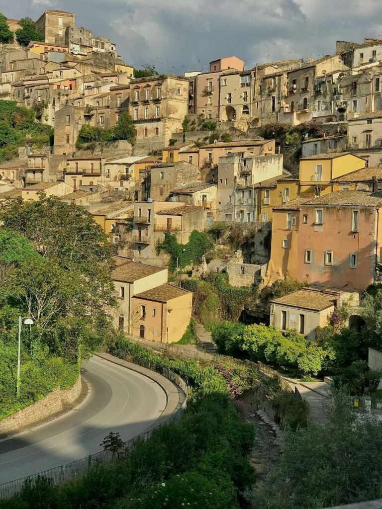 Hillside view of Ragusa's historic buildings under a cloudy sky