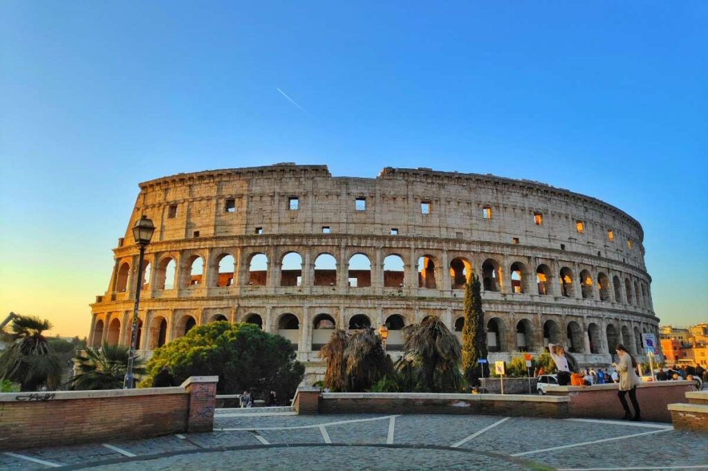 The exterior of Rome's Colosseum at sunset, with a clear sky and warm lighting